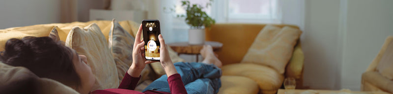 Person laying on sofa controlling wifi thermostat