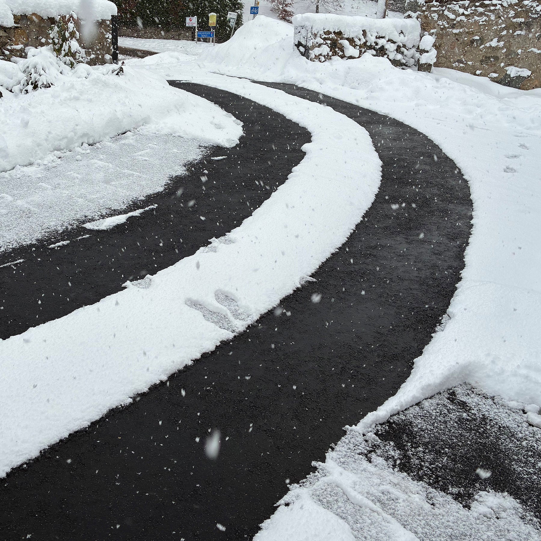 Snow-covered driveway and car in a residential area during a snowfall, with the snow melted from the Snowtec system