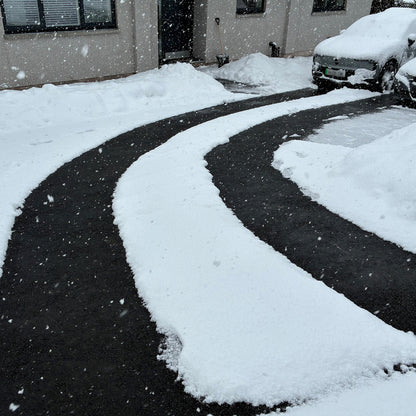 Snow-covered driveway and car in a residential area during a snowfall, with the snow melted from the Snowtec system